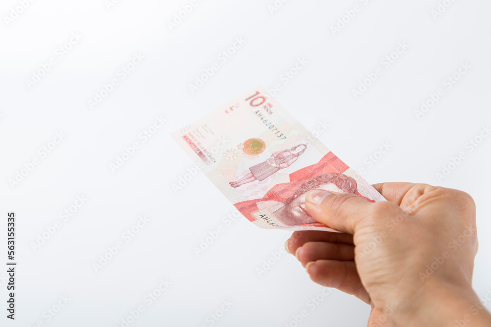 a person hands over a ten thousand colombian pesos bill. white background. a person hands over a ten thousand colombian pesos bill. white background.