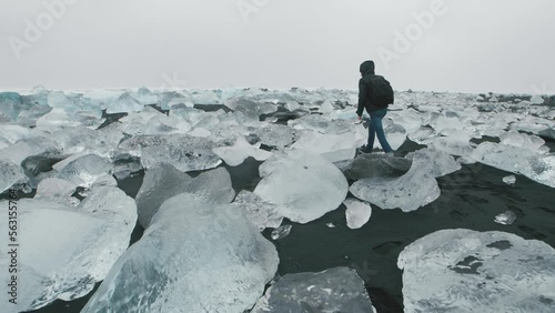 Man walking on Diamond beach in Iceland around Jokulsarlon Iceberg beach. Crystal ice melting on volcanic beach In Iceland.