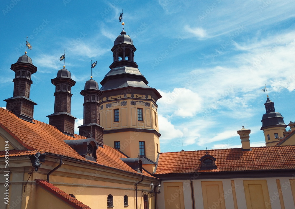 Spiers with family coats of arms and symbols, lookout towers and high walls of a medieval castle in Eastern Europe against the backdrop of a summer blue sky. Family nests of the Radzivils in Europe.