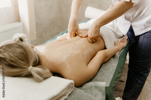 Professional doctor physiotherapist makes a back massage to a young woman. Therapeutic massage in the physiotherapist's office.