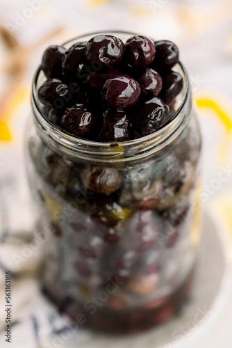 Various olives flavored with spices in white cup and glass jar. Green olives, black olives. Front and top shot on a white background	
