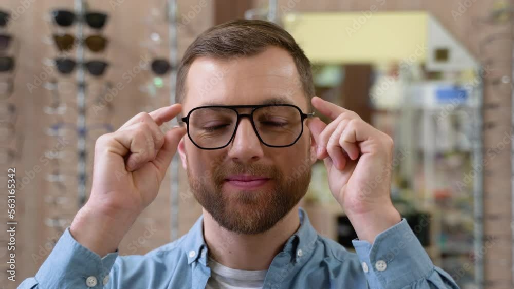 Portrait of handsome bearded guy picking new specs at optical shop. Choosing glasses concept Portrait of handsome bearded guy picking new specs at optical shop. Choosing glasses concept