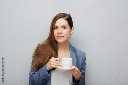 Business woman wearing suit holding coffee cup with saucer.