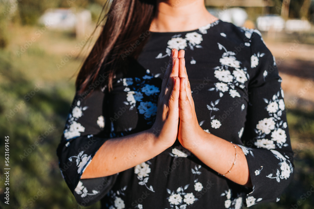Unrecognizable believer woman with praying hands at sunset in the field. Communion with Godc Unrecognizable believer woman with praying hands at sunset in the field. Communion with Godc