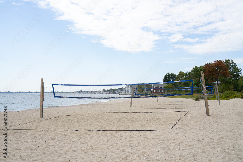 Empty beach with volleyball nets set up for playing. Houses along the shore in Connecticut