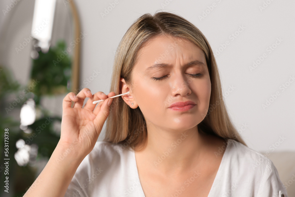 Young woman cleaning ear with cotton swab at home Young woman cleaning ear with cotton swab at home