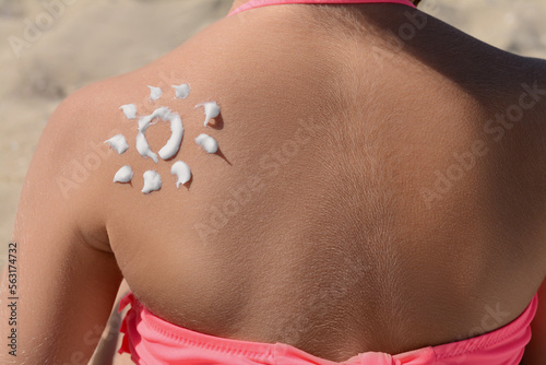 Little girl with sun protection cream on body outdoors, closeup