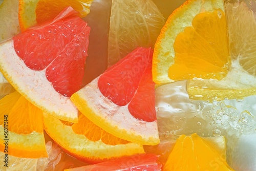 Slices of grapefruit, orange fruit and honey pomelo in water on white background. Pieces of grapefruit, orange fruit and honey pomelo in liquid with bubbles. 