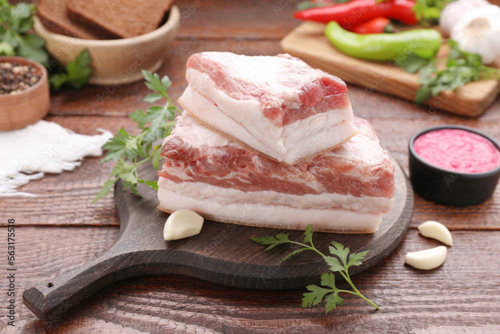 Pieces of tasty pork fatback with garlic and parsley on wooden table Pieces of tasty pork fatback with garlic and parsley on wooden table