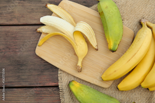Whole and cut bananas on wooden table, flat lay. Space for text