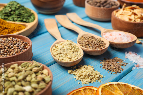 Many different spices on light blue wooden table