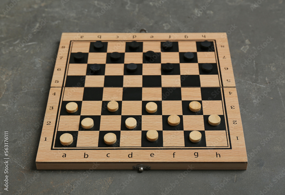 Wooden checkerboard with game pieces on grey table Wooden checkerboard with game pieces on grey table