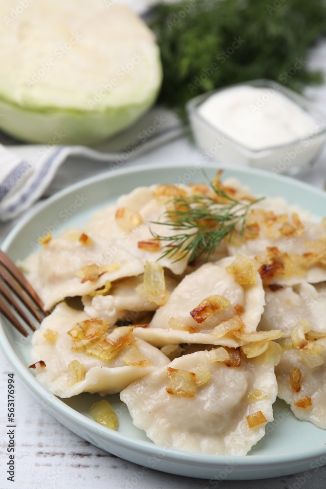 Cooked dumplings (varenyky) with tasty filling, fried onions and dill on wooden table, closeup