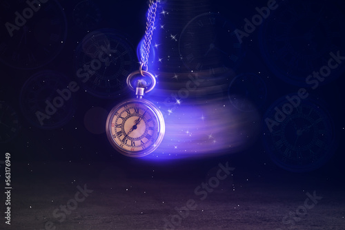 Hypnosis session. Vintage pocket watch with chain swinging over surface on dark background among faded clock faces, magic motion effect photo