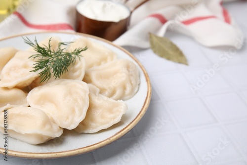 Cooked dumplings (varenyky) with tasty filling and dill on white table, closeup. Space for text