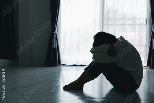 Concept of sad teenage girl depression. Upset teenage girl sitting at floor indoors. Anxiety young woman Despair and stress. Lonely and unhappy female are social victims. loneliness youth in home. photo