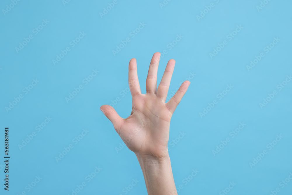Woman giving high five on light blue background, closeup