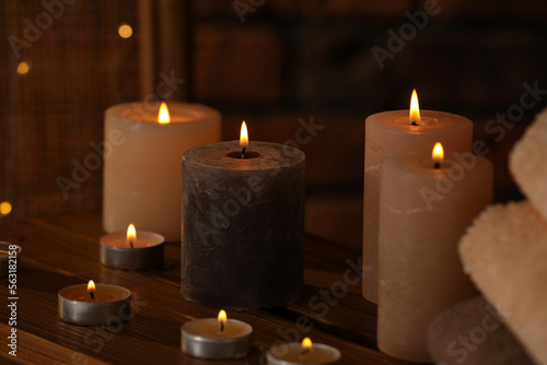 Spa composition with burning candles on wooden table in wellness center, closeup