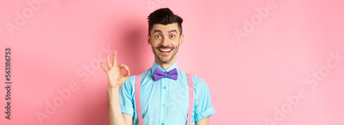 Handsome caucasian man with moustache smiling and showing okay sign, approve something good, praising excellent choice, standing amused on pink background