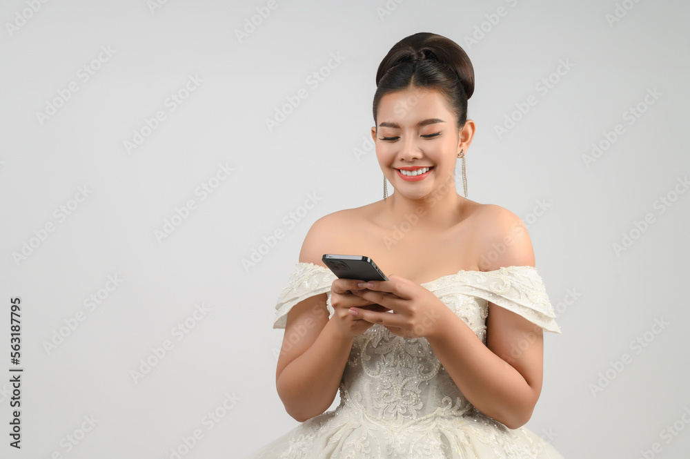 Young asian beautiful bride posting with smartphone in hand
