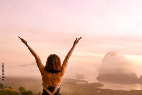 Senior woman raising hands up in the air, feeling happiness, freedom, victory with small island in ocean background, breathing the pure ozone when traveling. Journey, lifestyle, love, victory concept.