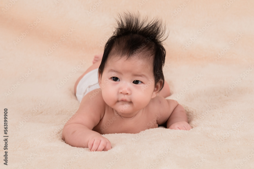 Asian newborn baby 3 month lying prone on beige soft bed. healthy