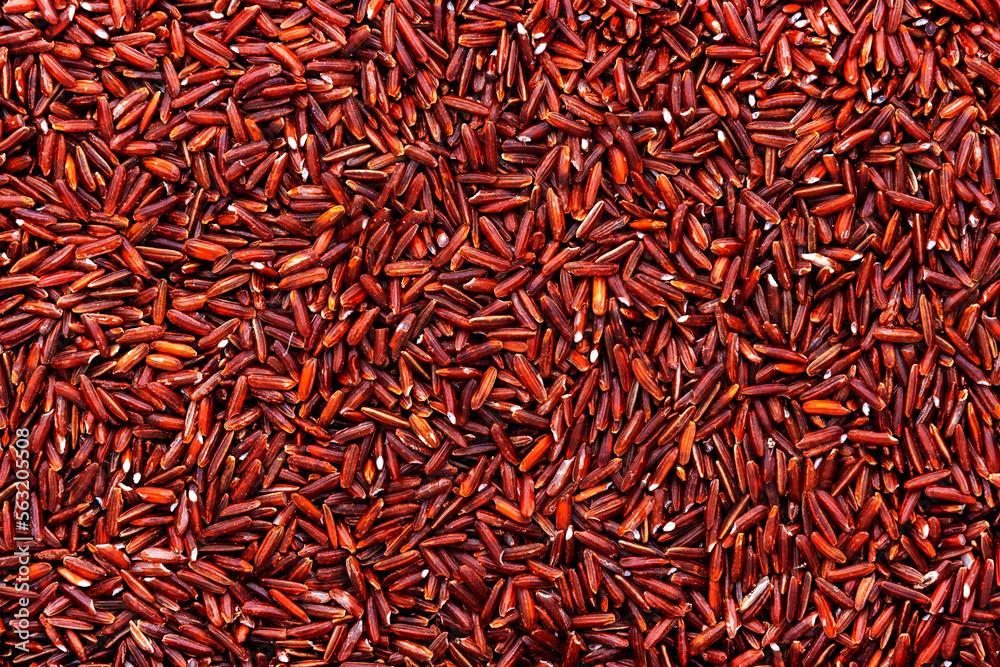 Wild raw red rice groats, food background texture, top view