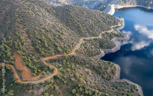 Drone aerial of rural curved road passing through the mountain. and reservoir dam. Discovery and adventure in nature photo