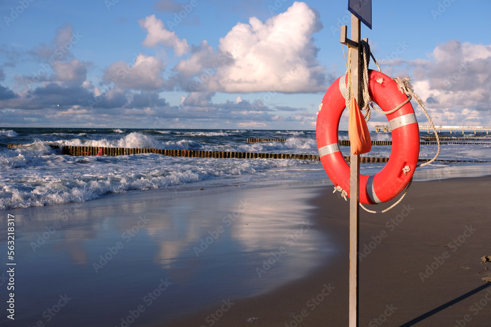 Close up view of life preserver on the stand on sandy beach near storming sea waves