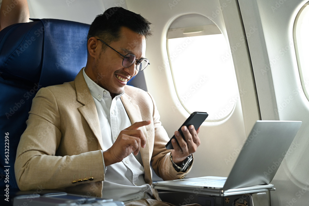 Smart millennial businessman passengers hands typing text on smart phone while sitting near window in an airplane