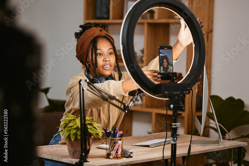 Communication, phone and influencer live streaming podcast, radio talk show or speaker talk about teen culture. Presenter microphone, black woman setup broadcast or speaking about online student news photo