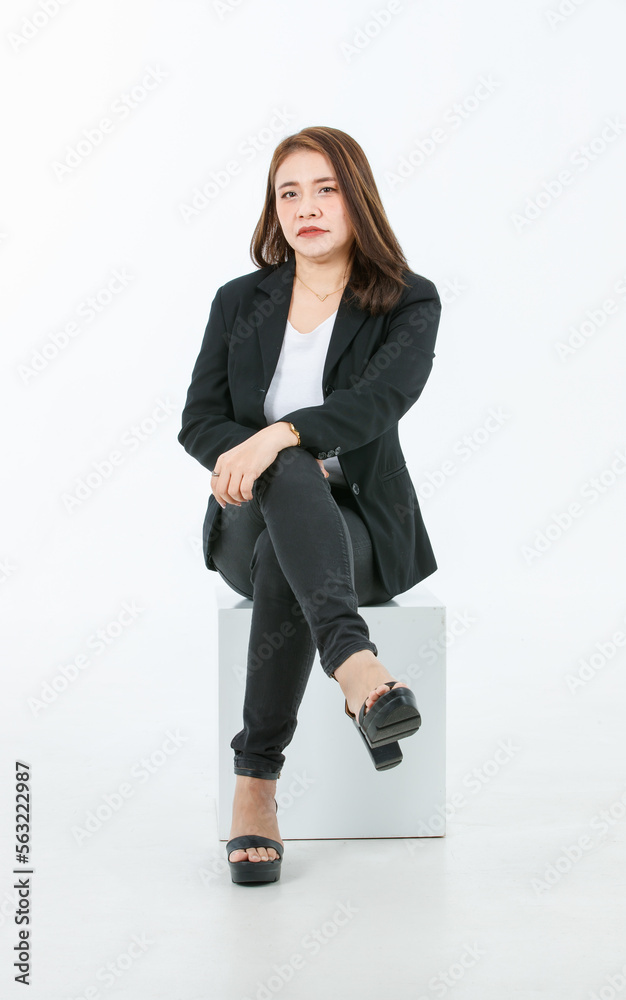 Portrait isolated cutout studio full body shot of Asian confident female professional successful businesswoman in formal black suit high heels sitting on square box look at camera on white background Portrait isolated cutout studio full body shot of Asian confident female professional successful businesswoman in formal black suit high heels sitting on square box look at camera on white background