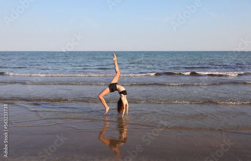 young slim athletic girl performs gymnastic exercises in summer photo