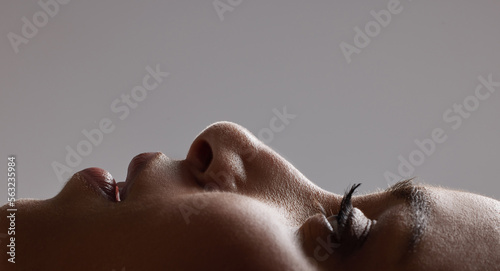 Closeup face of beautiful woman smooth, soft and healthy skin against studio background. Headshot of attractive, trendy and edgy model with natural eyelashes and skincare cosmetics for anti aging