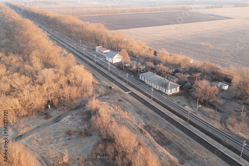 A deserted train station without people in late autumn. Railway station among the fields in autumn: several old buildings and a railway - high angle view.