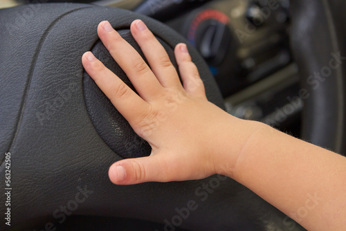 child presses the horn in the car,The kid presses the signal button located on the steering wheel of the car