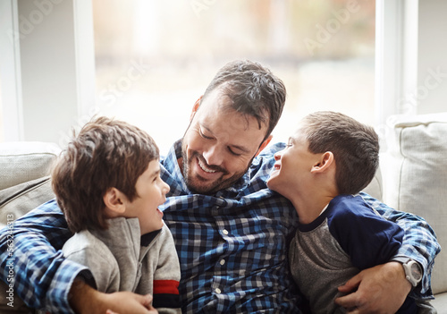 Family home, boys and dad with hug on sofa for conversation, love or bonding for childhood development. Happy people, relax or joke together in living room for fun, happiness or quality time in house