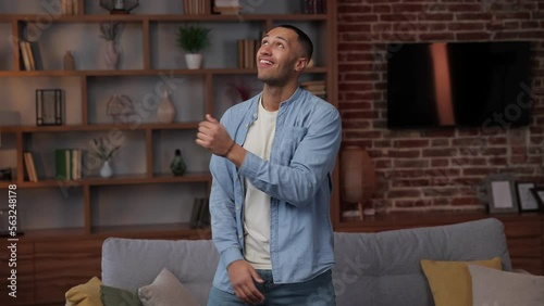Active carefree young african american man is dancing in the living room, attractive happy guy having fun spends free time. He is energetically moving listening fovourite song, dancing with joy, celeb