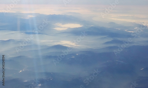View of the mountains in the fog at dawn from the airplane window. Beautiful wallpaper.