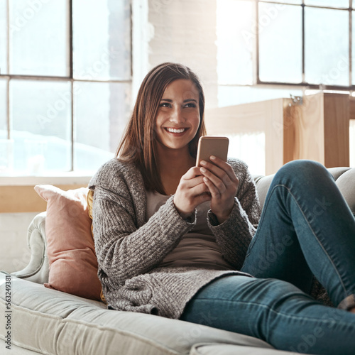 Thinking, phone and woman relax on a sofa, happy and smile while chatting online in her home. Idea, girl and smartphone app for online dating, social media and streaming while resting in living room