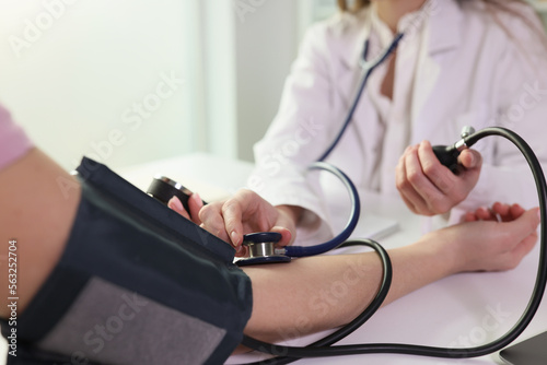 Doctor measuring blood pressure to patient using mechanical sphygmomanometer in clinic closeup photo