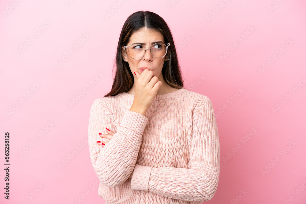 Young Italian woman isolated on pink background With glasses and having doubts Young Italian woman isolated on pink background With glasses and having doubts