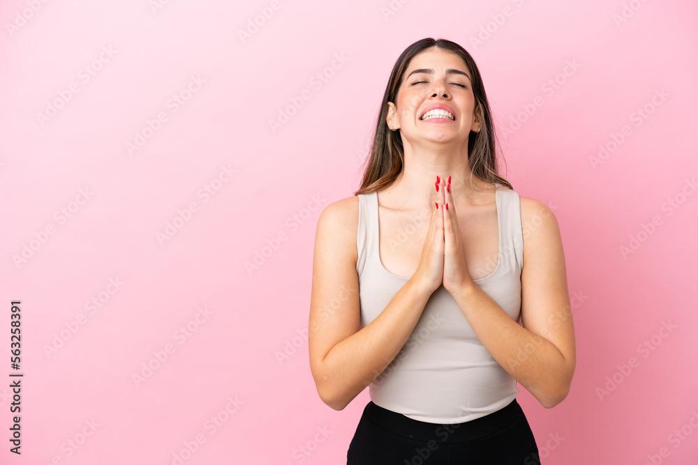 Young Italian woman isolated on pink background keeps palm together. Person asks for something Young Italian woman isolated on pink background keeps palm together. Person asks for something