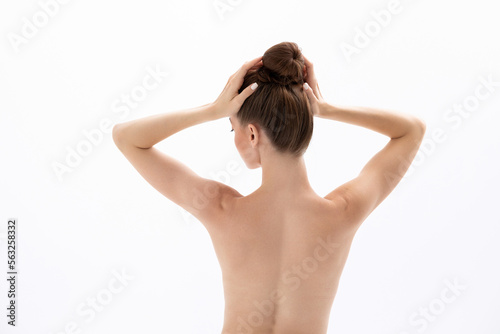A young woman touches her head and demonstrates products for hair and skin.