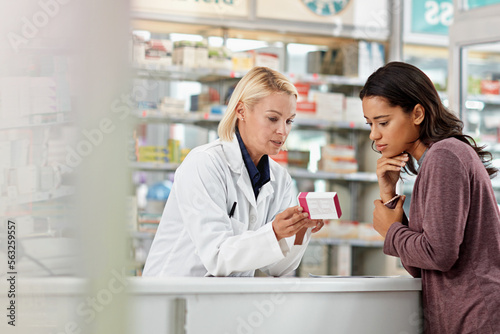 Consulting customer and focus of store pharmacist at counter for expert help and customer service. Pharmaceutical advice and opinion of worker helping girl with medicine information at pharmacy.