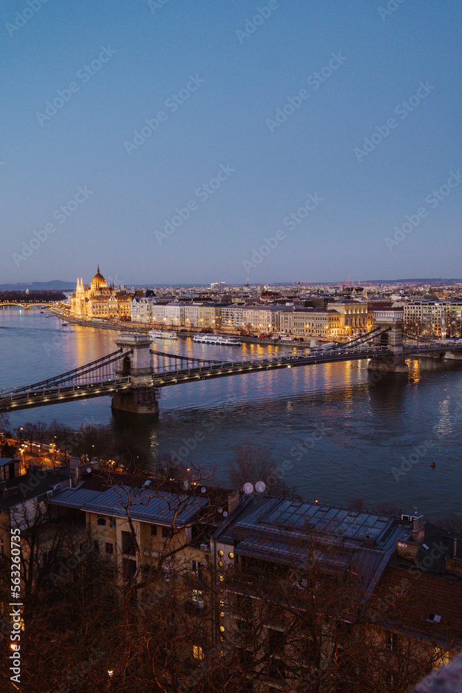 Fototapeta premium Night view of Budapest showcasing illuminated buildings, bridges, and reflections on the Danube River at dusk
