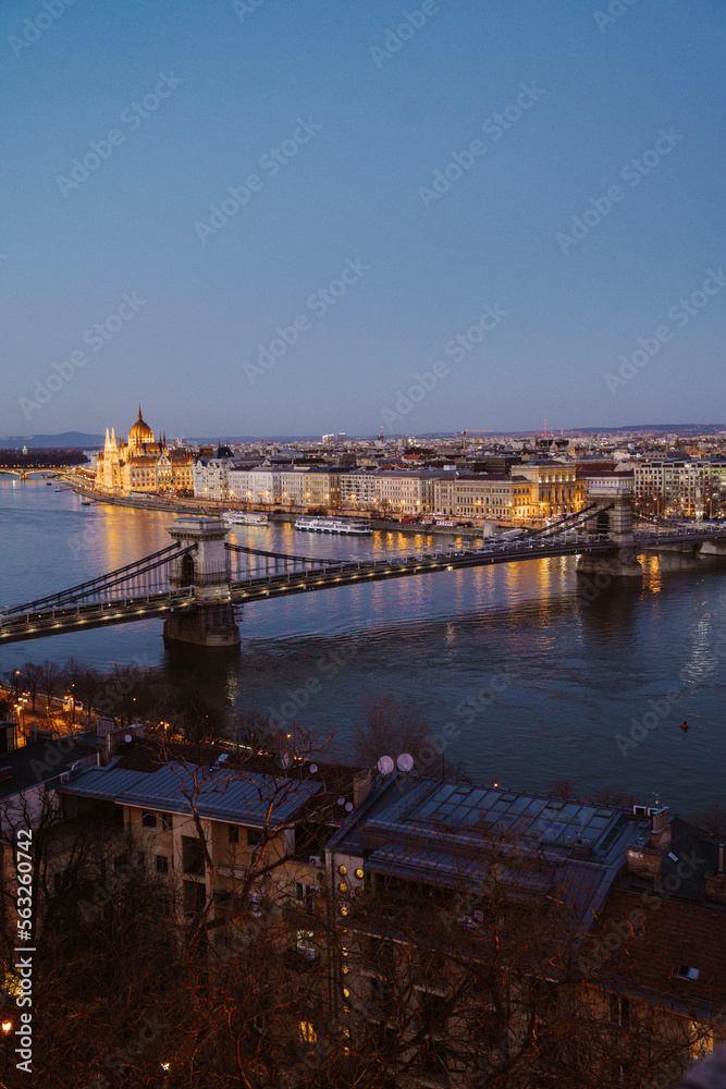 Fototapeta premium Night view of Budapest showcasing illuminated buildings, bridges, and reflections on the Danube River at dusk