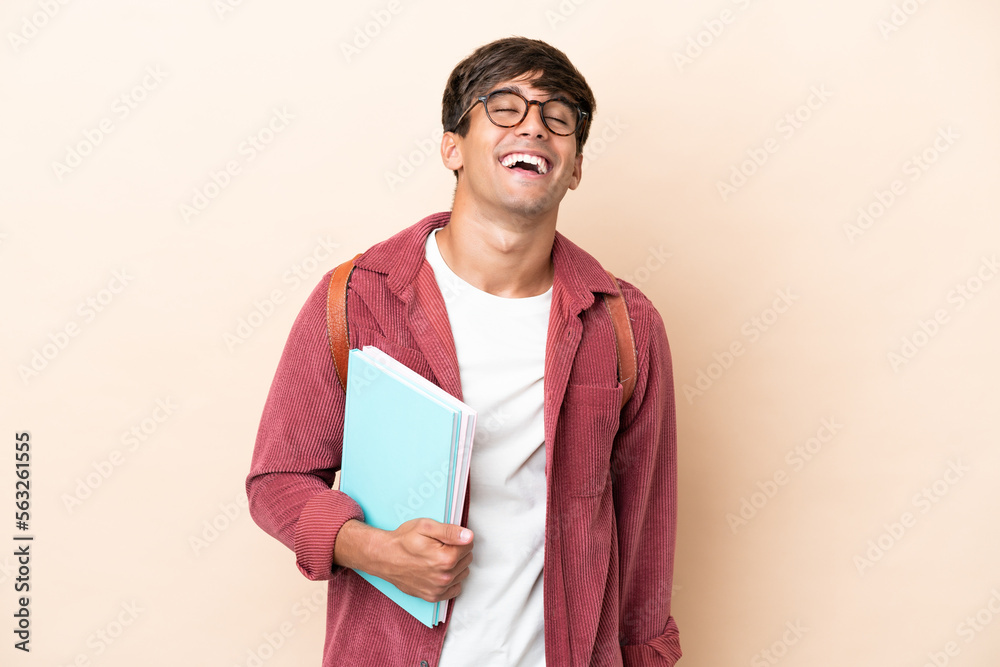 Young student caucasian man isolated on ocher background laughing Young student caucasian man isolated on ocher background laughing