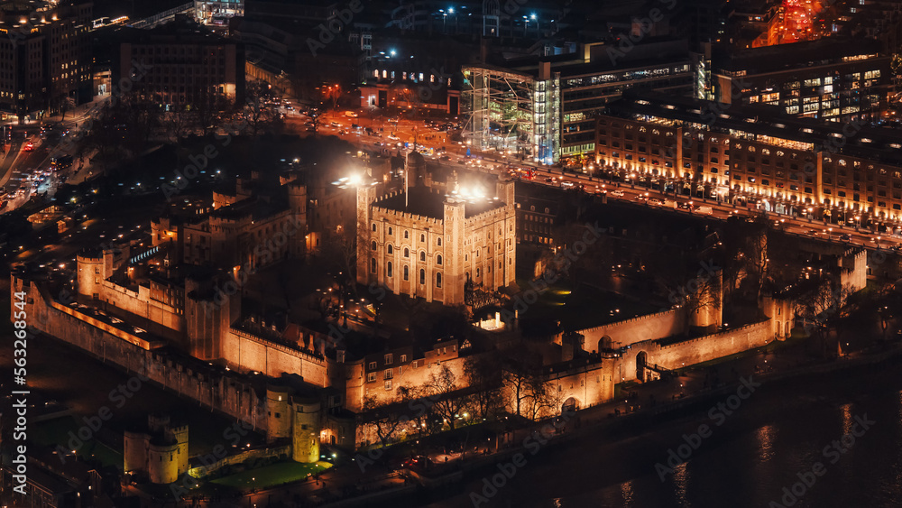 Aerial view of illuminated London tower, orange yellow street lights starting glowing to streets