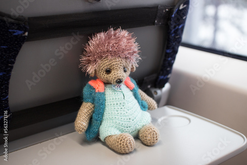 a hand-knitted hedgehog on a folding table on the train